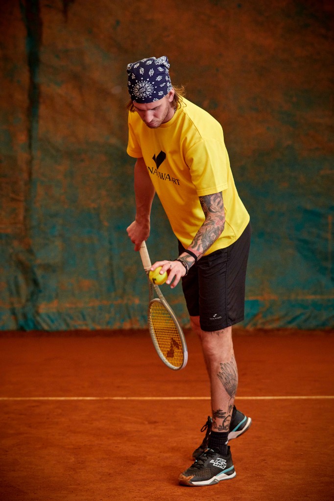 クレーコートでスノワートのウェアを着用したテニスプレイヤー